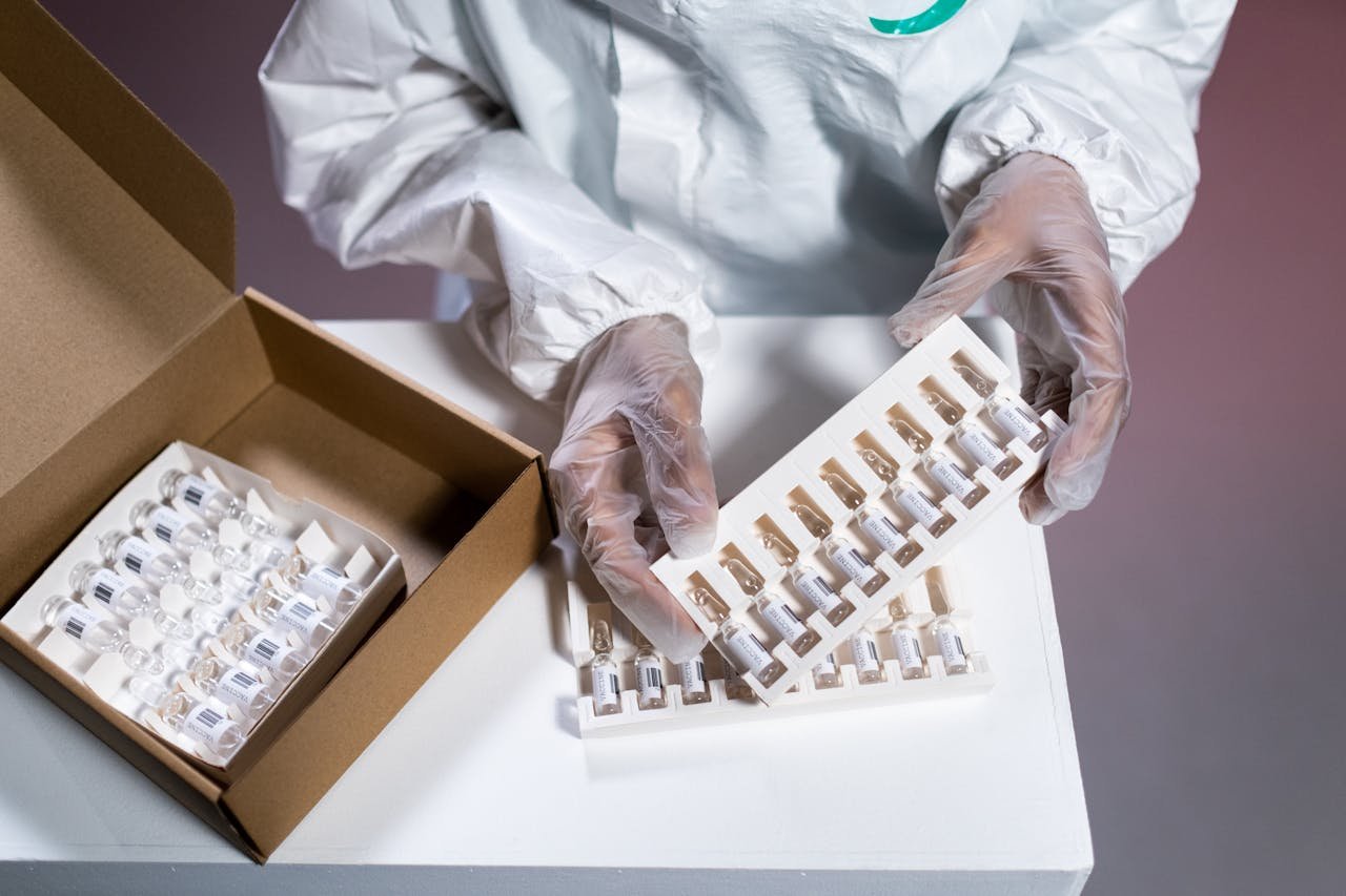 A healthcare professional wearing gloves handles vaccine vials, emphasizing safety and precision.
