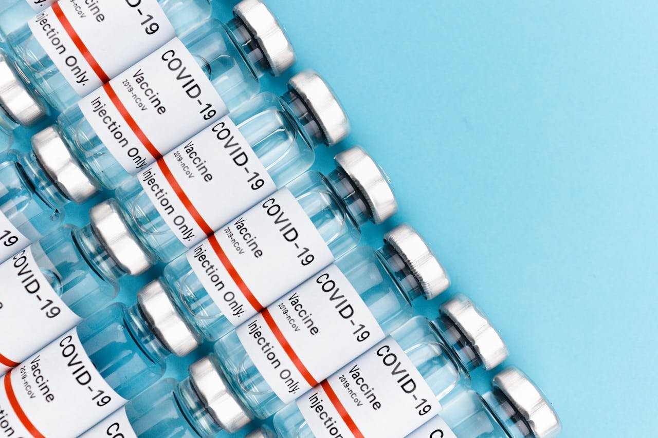 Close-up of COVID-19 vaccine vials arranged on a blue surface.